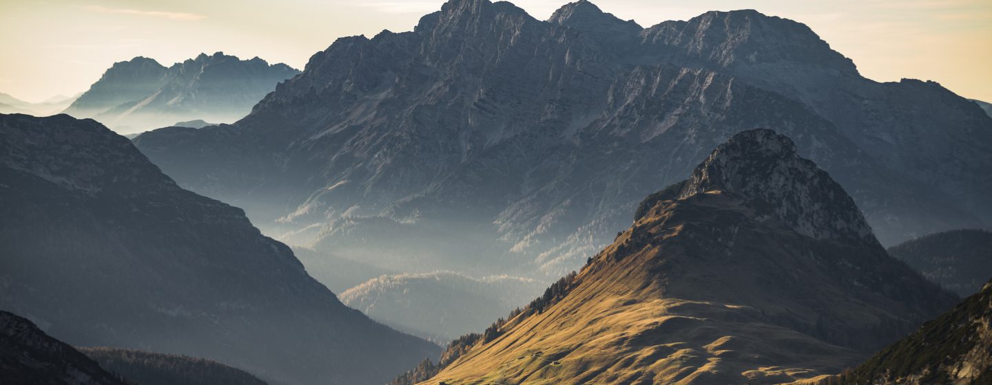 Late autumn sunset with warm sunlight on alpine pastures and the Austrian mountain cliffs and peaks of Loferer Steinberge